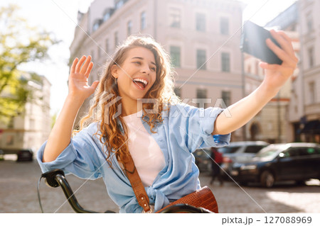 Woman using mobile phone while walks with a bicycle. Selfie time. People, blogging and lifestyle. 127088969