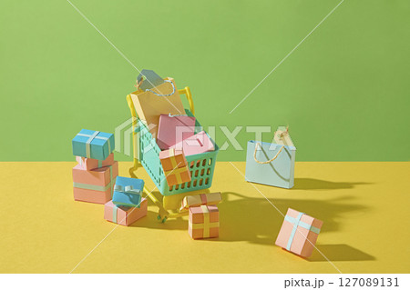 Paper cutout of a shopping cart filled with goods, symbolizing online grocery shopping with convenience and creativity in a green-yellow background. Paper cutout of a shopping cart filled with goods, symbolizing online grocery shopping with convenience and creativity in a green-yellow background. 127089131