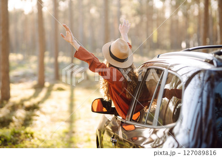 Young woman leaning out of the car window enjoying nature. Road trips summer holidays. 127089816