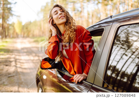 Young woman leaning out of the car window enjoying nature. Road trips summer holidays. 127089848