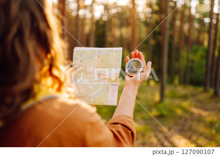 Traveler young woman searching direction with a compass on background of map in the forest. 127090107