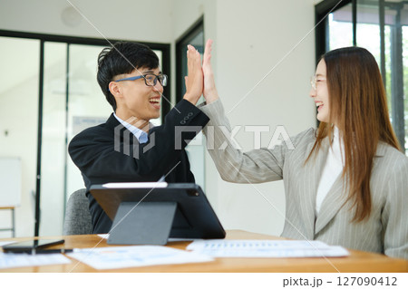 Two business people discuss financial strategy and collaborate with colleagues. Two business people discuss financial strategy and collaborate with colleagues. 127090412