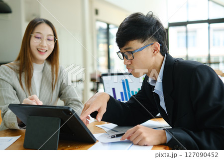 Two business people discuss financial strategy and collaborate with colleagues. 127090452