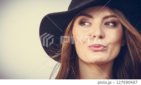 Smiling pretty girl with brown hair and black hat. 127090487