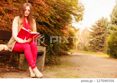 Woman relaxing in autumnal park reading book Woman relaxing in autumnal park reading book 127090508