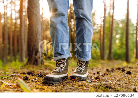 Feet of an adult wearing boots to travel walking in the forest. Feet walking in outdoor nature 127090534
