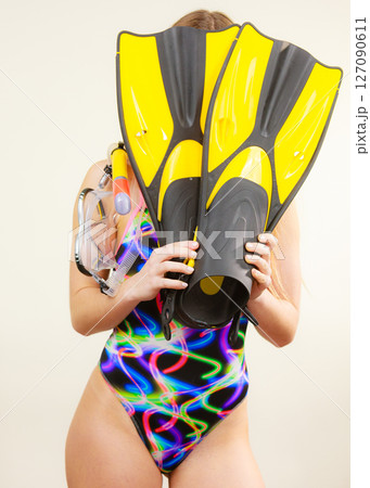 Woman covering her face with flippers having fun Woman covering her face with flippers having fun 127090611