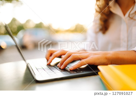 Close-up of woman hands working on laptop outdoors. Freelancing concept, business. 127091027