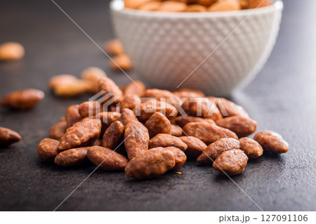 Nuts coated in sugar and honey on black table. 127091106