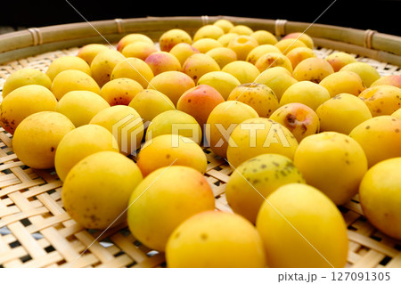 竹のざるに並んだ粒の大きい完熟した梅の果実_10 127091305
