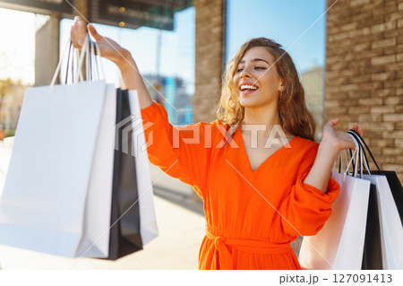 Young woman with shopping bags near mall. Purchases, shopping, lifestyle, sale concept. Young woman with shopping bags near mall. Purchases, shopping, lifestyle, sale concept. 127091413