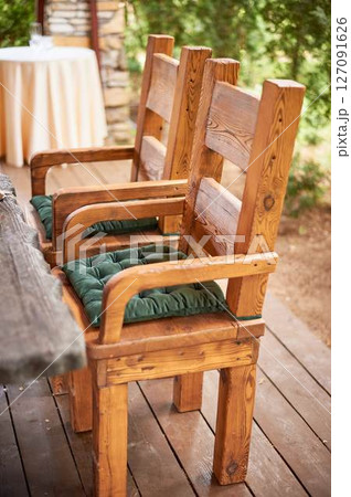 Wedding decoration in the Slavic style. Sturdy wooden thrones, chairs with green cushions 127091626