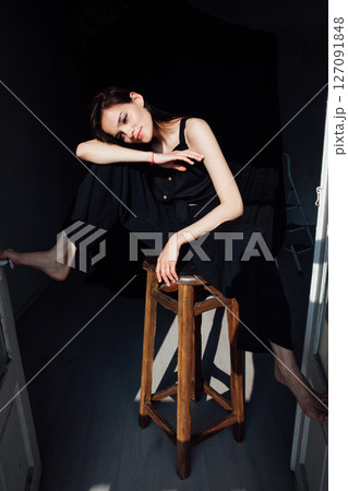 fashionable woman in black clothes sitting on chair in room fashionable woman in black clothes sitting on chair in room 127091848