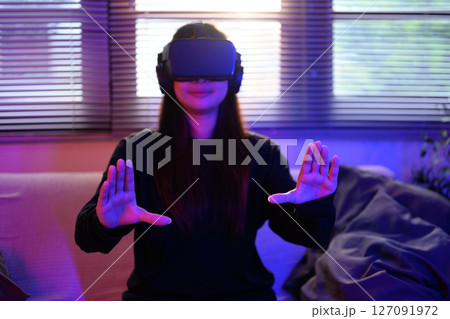 Smiling young woman interacts with virtual reality through her VR headset 127091972