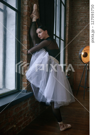 Elegant ballerina stretching gracefully in a beautiful and artistic studio setting 127093750