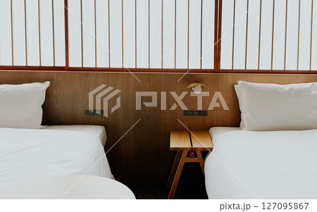 Minimalist Japanese hotel room with twin beds and soft white bedding, shoji screen. Modern ryokan interior  127095867