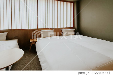 Minimalist Japanese hotel room with twin beds and soft white bedding, shoji screen. Modern ryokan interior  127095871