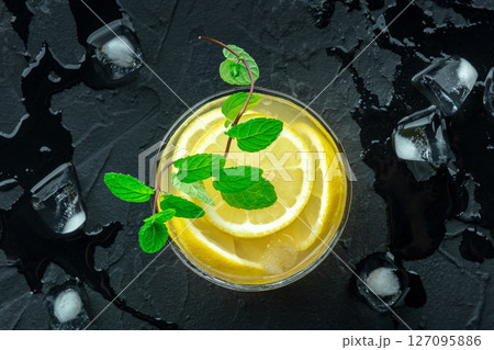 A glass of fresh lemonade, a mocktail with lemon juice, on a black background 127095886