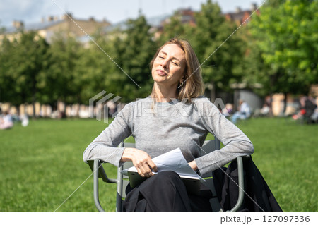 Happy relaxed woman soaking up sunny weathe in grassy park, taking time off from work in nature 127097336