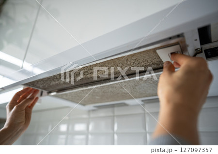 Dirty greasy oil exhaust filter held by homeowner, long overdue for cleaning. Health risks, bacteria 127097357