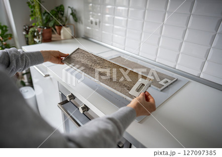 Metal mesh filter struggles with heavy grease due to regular frying. Man holding greasy oily grid Metal mesh filter struggles with heavy grease due to regular frying. Man holding greasy oily grid 127097385
