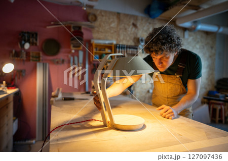 Joiner test sturdier lamp prototype in workshop. Thicker plywood base, vibration resistance check 127097436
