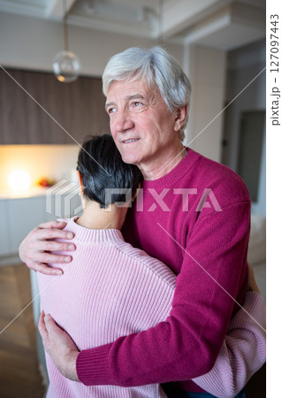 Cheerful senior man hugging wife with love. Elderly couple joy, marital care, calm aging together 127097443
