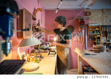 Woodworker placing tools back in order after finishing task, clearing workstation. Maintaining space 127097444