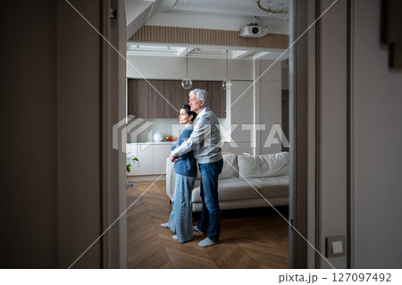 Elderly loving couple hugging looking out window. Mature romance support, aging together with trust 127097492