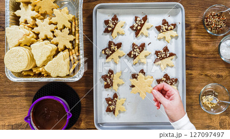 Flat lay. Creating snowflake-shaped cutout sugar cookies, dipped in chocolate, and adorned with different toppings. 127097497