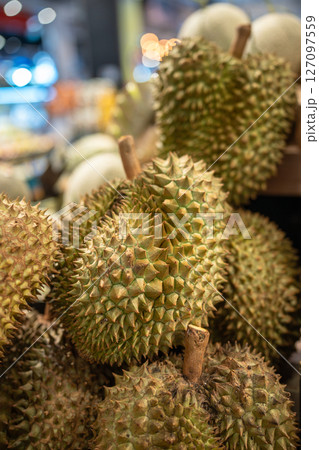 Durian fruits on supermarket shelf ready for customer selection, close up. Grocery stalls in Asia Durian fruits on supermarket shelf ready for customer selection, close up. Grocery stalls in Asia 127097559