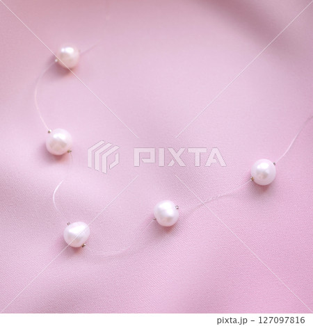 Pearl necklace on pink fabric background with soft light 127097816
