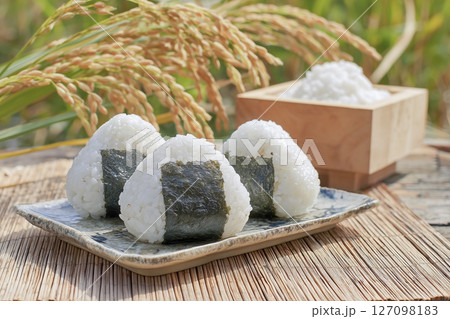 秋に収穫した新米で作ったおにぎりと田んぼの稲穂 127098183