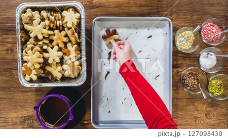 Flat lay. Creating snowflake-shaped cutout sugar cookies, dipped in chocolate, and adorned with different toppings. Flat lay. Creating snowflake-shaped cutout sugar cookies, dipped in chocolate, and adorned with different toppings. 127098430