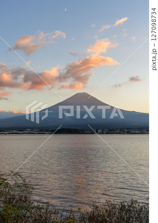 Golden hues of sunset highlight Mount Fuji slopes as scattered clouds float above Golden hues of sunset highlight Mount Fuji slopes as scattered clouds float above 127098734