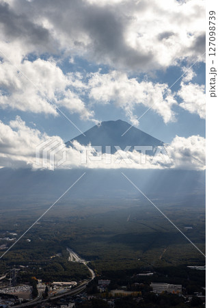 Mount Fuji emerges from drifting clouds with sun rays streaming down over Fujikawaguchiko Mount Fuji emerges from drifting clouds with sun rays streaming down over Fujikawaguchiko 127098739