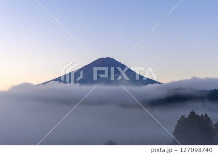 Mount Fuji emerging from a dense morning fog at sunrise, with soft light illuminating 127098740