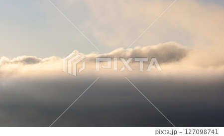Layers of mist and clouds illuminated by the soft morning sunlight 127098741