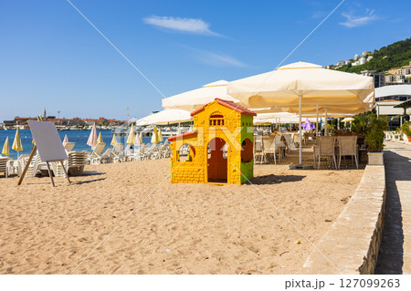 Plastic playhouse on sandy beach near umbrellas and loungers. Summer recreation, family tourism, and kid-friendly coastal environment. Plastic playhouse on sandy beach near umbrellas and loungers. Summer recreation, family tourism, and kid-friendly coastal environment. 127099263