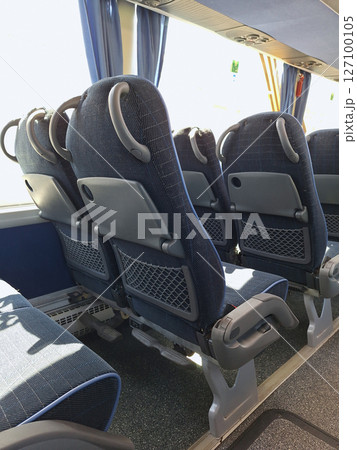 Empty bus interior with modern blue reclining seats and tray tables Empty bus interior with modern blue reclining seats and tray tables 127100105