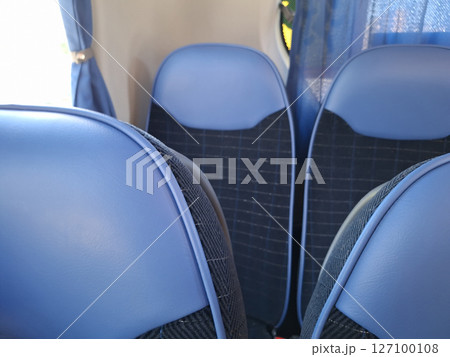 Empty blue bus seats with blue curtains in passenger vehicle interior 127100108