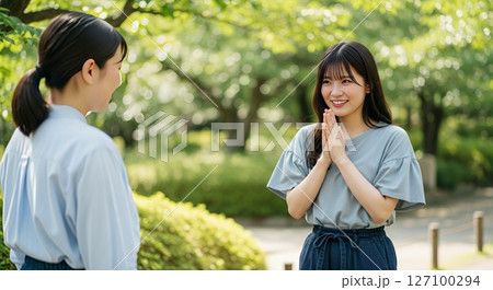 友人に何かをお願いしている女性 127100294