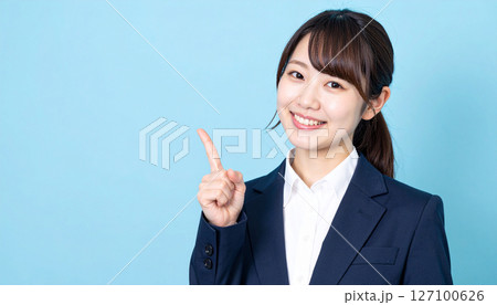 明るい笑顔で指さし説明するスーツ姿の若い女性 127100626