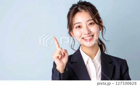 明るい笑顔で指さし説明するスーツ姿の若い女性 127100628