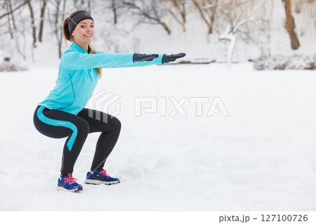 Winter workout. Girl wearing sportswear doing squats 127100726