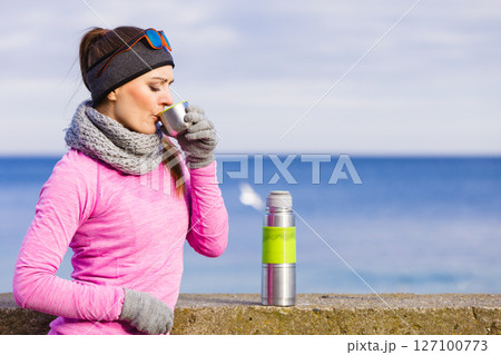 Fit woman in cold day warming up drink tea 127100773