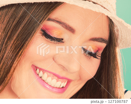 Woman face colorful eyes makeup, summer straw hat smiling 127100787