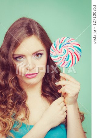 Smiling girl with lollipop candy on teal 127100853