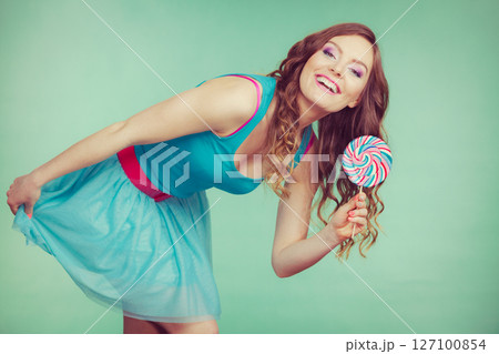 Smiling girl with lollipop candy on teal 127100854