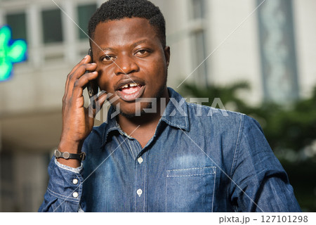 close-up of young african man with mobile phone, happy. 127101298